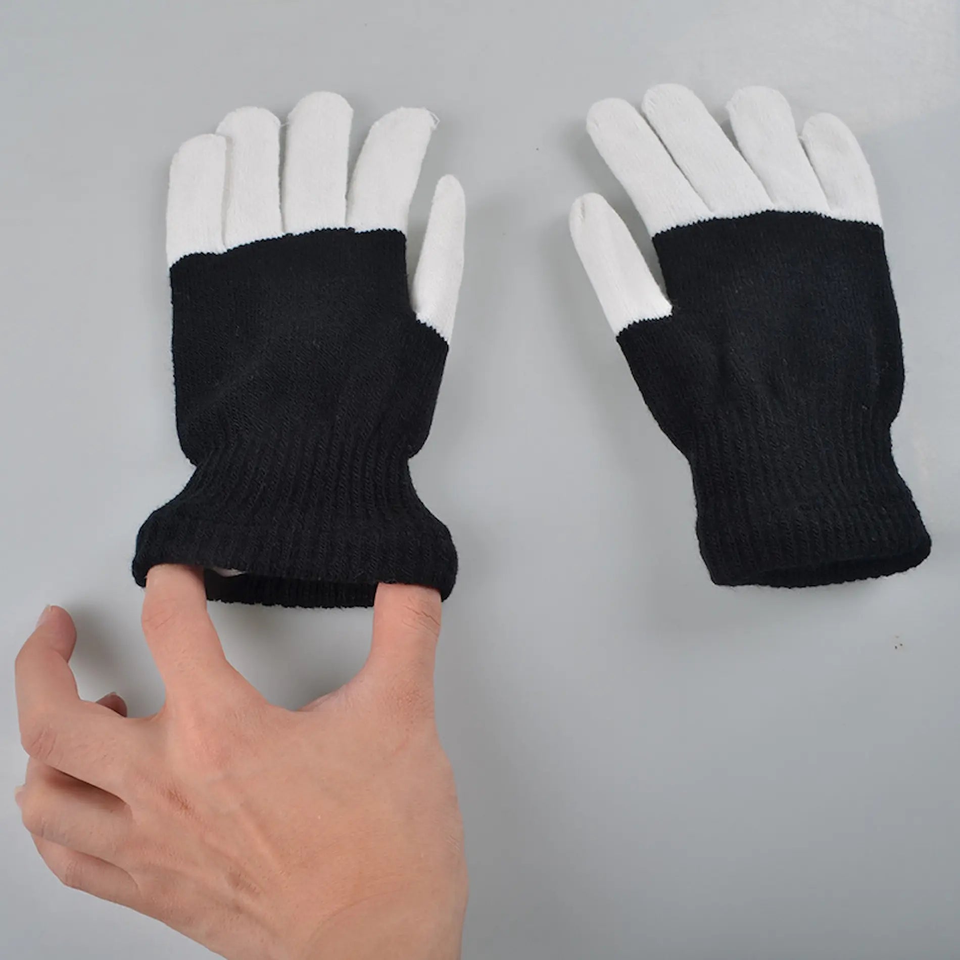Black gloves with white fingertips held by a hand