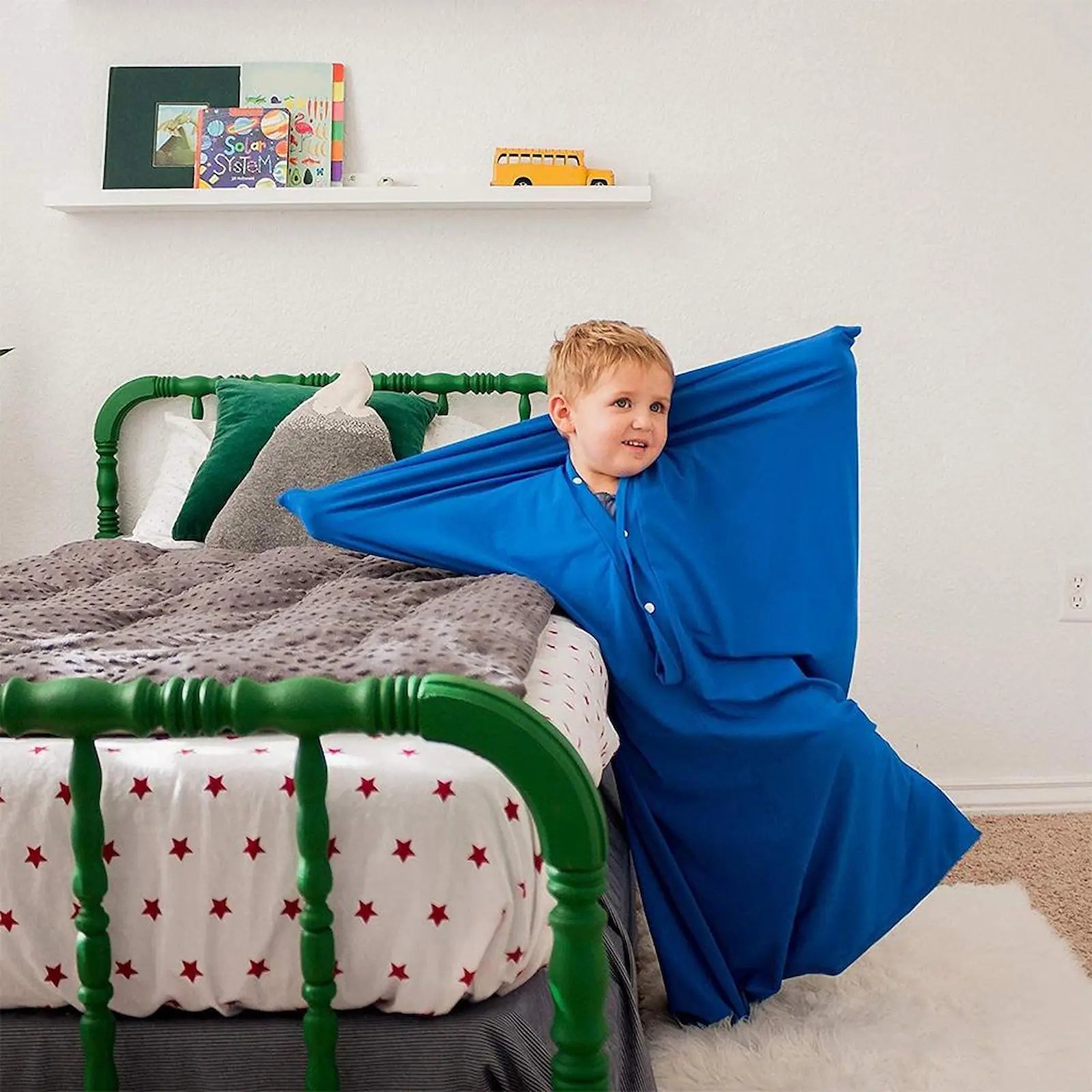 Child in a blue robe leaning against a bed