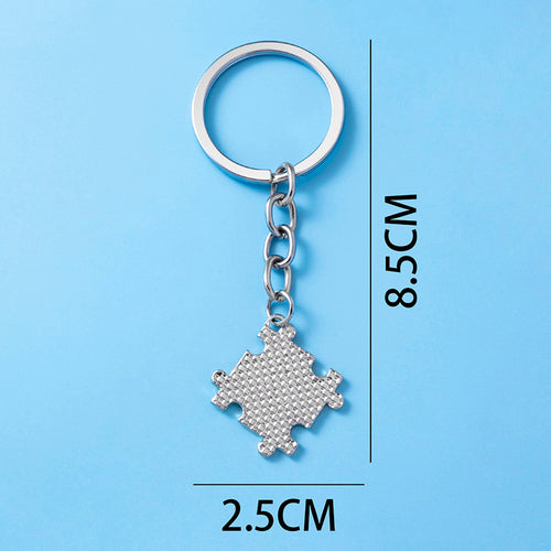 Silver puzzle piece keychain with textured surface on blue background, 8.5cm by 2.5cm