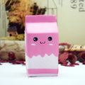 Pink milk carton plush toy with a cute face on a blurred background